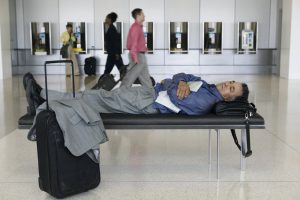 man sleeping on bench in airport