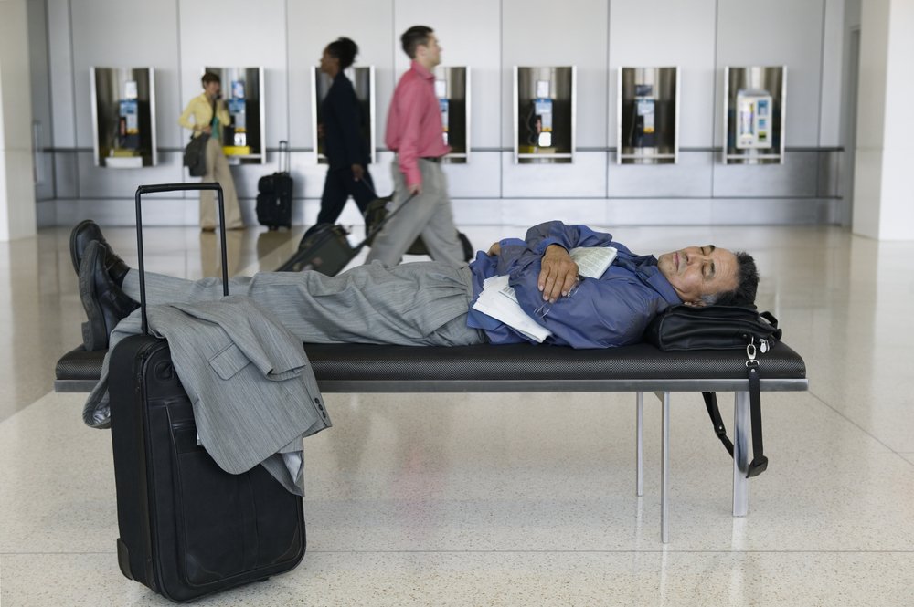 man sleeping on bench in airport